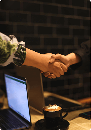 Handshake over a desk with coffee